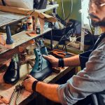 Cobbler is repairing shoes for customers Experienced shoemaker is creating retro leather shoes at his comfortable workshop.