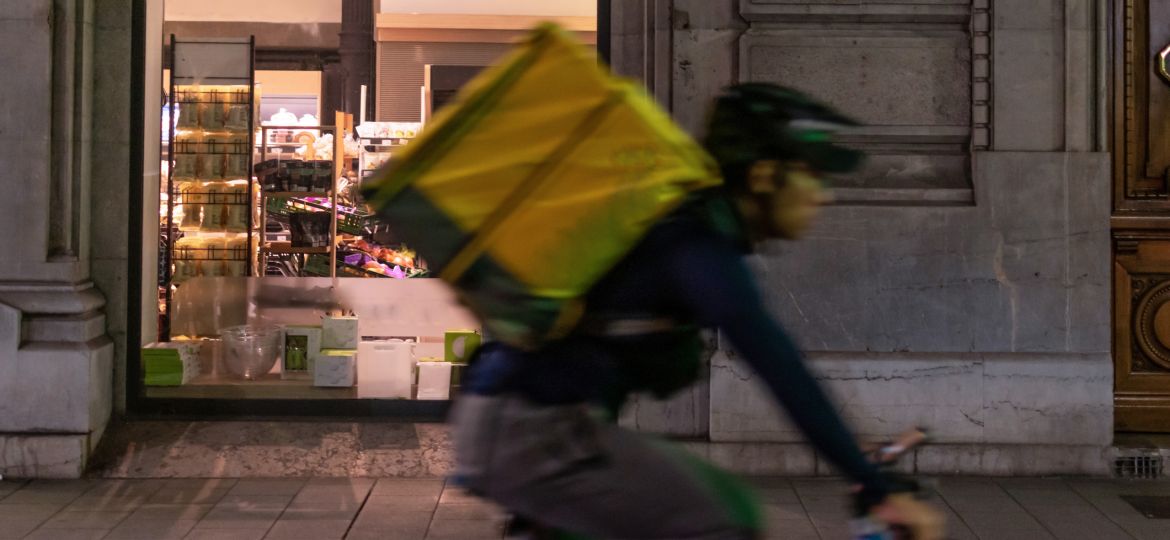 Delivery man on a bicycle through the city center at night